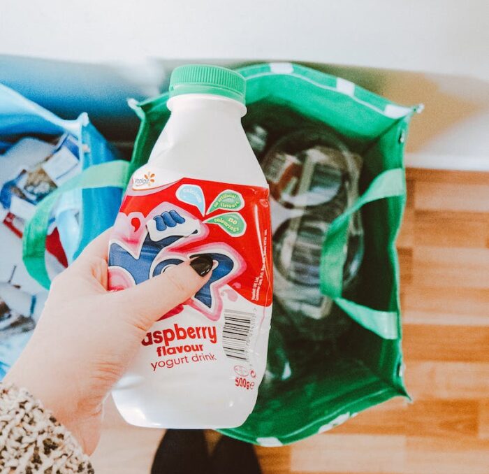 Person Holding Red and White Disposable Bottle